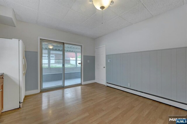 128 Prospect, Midland Park, NJ 07432 - empty room featuring baseboard heating, light wood-type flooring, a wainscoted wall, and baseboards
