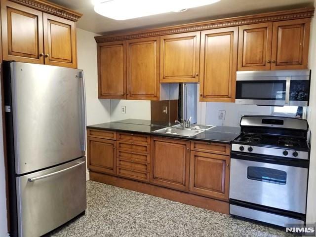 1575 Center Ave Unit 4B, Fort Lee, NJ 07024 - kitchen featuring appliances with stainless steel finishes, dark countertops, brown cabinets, and a sink