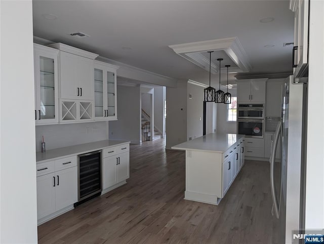 265 Adams Ave, River Edge, NJ 07661 - kitchen with beverage cooler, stainless steel appliances, white cabinetry, light wood finished floors, and crown molding