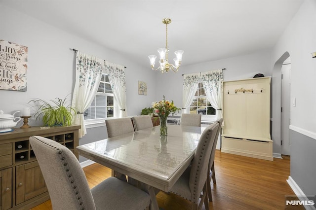 101 Pasadena Pl, Hawthorne, NJ 07506 - dining room featuring a chandelier, arched walkways, light wood-style floors, and baseboards
