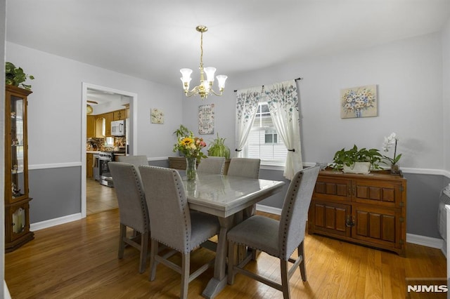 101 Pasadena Pl, Hawthorne, NJ 07506 - dining area with a chandelier, light wood finished floors, and baseboards