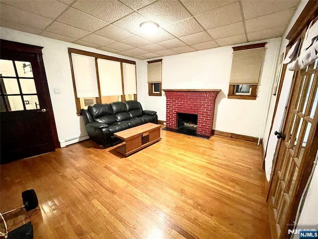 208 Wayne Ave, Cliffside Park, NJ 07010 - living room featuring baseboard heating, wood finished floors, a brick fireplace, baseboards, and a paneled ceiling