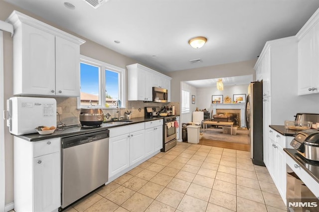 755 Jefferson Ave, Cliffside Park, NJ 07010 - kitchen featuring appliances with stainless steel finishes, dark countertops, a fireplace, and white cabinetry