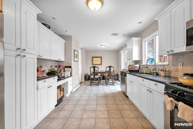 755 Jefferson Ave, Cliffside Park, NJ 07010 - kitchen featuring appliances with stainless steel finishes, a sink, dark countertops, tasteful backsplash, and white cabinets