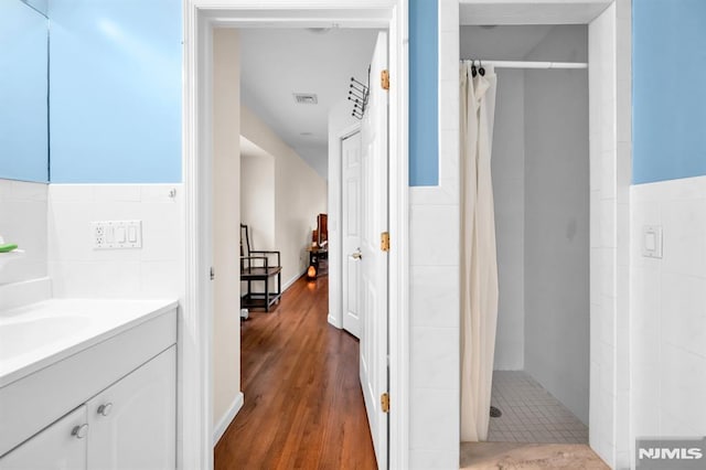 755 Jefferson Ave, Cliffside Park, NJ 07010 - bathroom featuring tile walls, a stall shower, wood finished floors, vanity, and a wainscoted wall