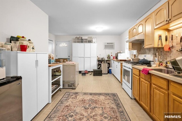 755 Jefferson Ave, Cliffside Park, NJ 07010 - kitchen featuring white range with gas cooktop, under cabinet range hood, refrigerator, light tile patterned floors, and a wall unit AC