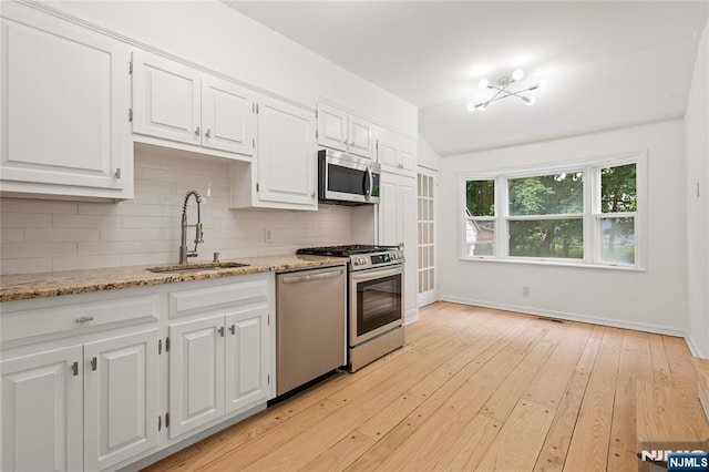 41 Oakland Ave, Westwood, NJ 07675 - kitchen featuring appliances with stainless steel finishes, a sink, decorative backsplash, white cabinets, and vaulted ceiling