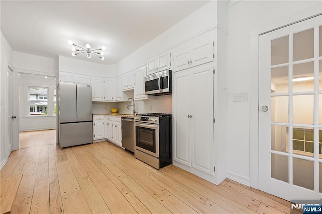 41 Oakland Ave, Westwood, NJ 07675 - kitchen featuring stainless steel appliances, a chandelier, white cabinetry, light wood-type flooring, and a sink