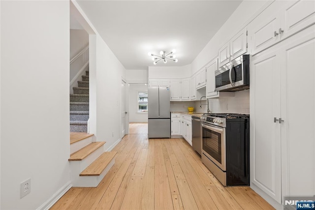 41 Oakland Ave, Westwood, NJ 07675 - kitchen with appliances with stainless steel finishes, white cabinets, a chandelier, light wood-type flooring, and baseboards