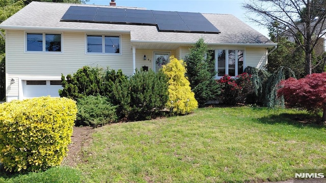 43 Carol Pl, Bloomfield, NJ 07003 - view of front of property featuring roof mounted solar panels, a garage, a front yard, and a shingled roof