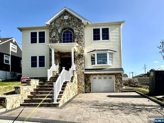 178 Leonard Pl, North Arlington, NJ 07031 - view of front facade featuring stone siding, decorative driveway, and an attached garage