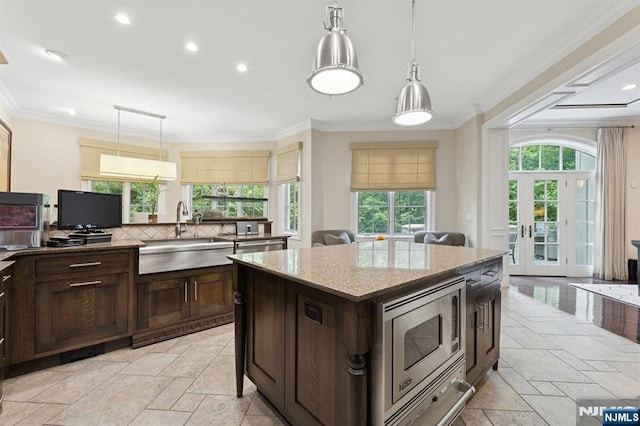 511 Bellaire Dr, Demarest, NJ 07627 - kitchen featuring a sink, stainless steel microwave, stone tile flooring, dark brown cabinets, and crown molding