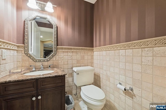511 Bellaire Dr, Demarest, NJ 07627 - half bath with toilet, a wainscoted wall, vanity, tile walls, and wallpapered walls