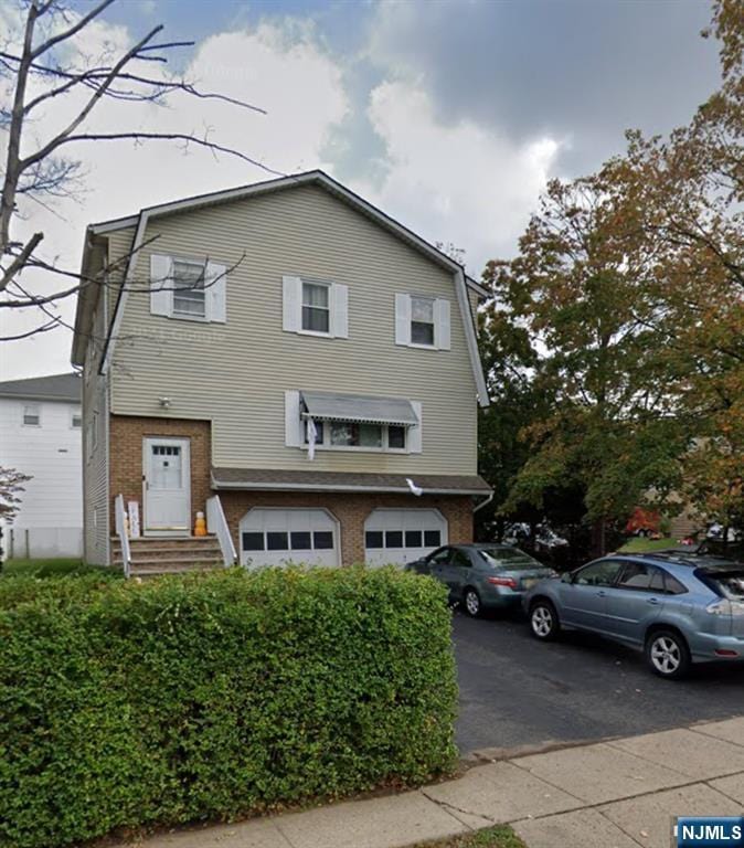 71 Miles St, Elmwood Park, NJ 07407 - colonial inspired home with a garage, a gambrel roof, brick siding, and driveway