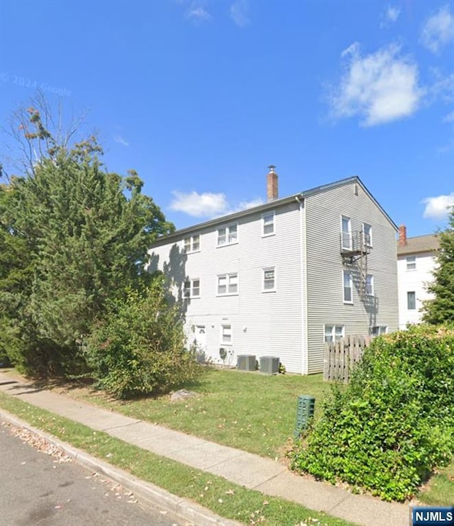 71 Miles St, Elmwood Park, NJ 07407 - view of side of home with a chimney, central air condition unit, and a lawn