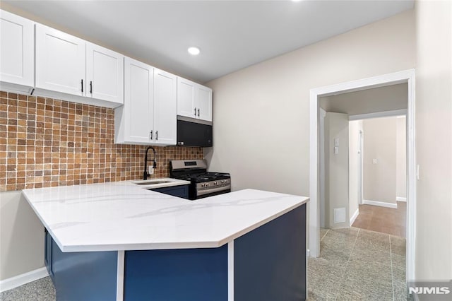 99 W 50th St, Bayonne, NJ 07002 - kitchen featuring stainless steel gas range oven, a sink, decorative backsplash, light stone countertops, and a peninsula