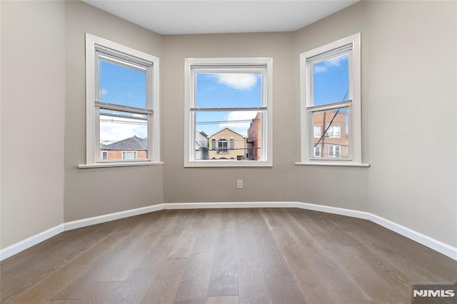 99 W 50th St, Bayonne, NJ 07002 - empty room with plenty of natural light, wood finished floors, and baseboards