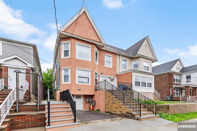 99 W 50th St, Bayonne, NJ 07002 - townhome / multi-family property with stairs, decorative driveway, stucco siding, and a garage