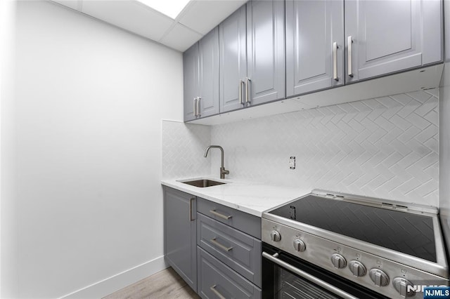 1111 River Rd Unit F25, Edgewater, NJ 07020 - kitchen with gray cabinets, stainless steel range with electric cooktop, a sink, decorative backsplash, and light stone countertops