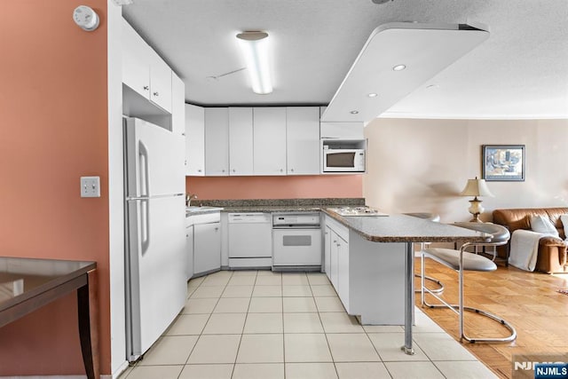 7004JFKB 70th Unit 40G, Guttenberg, NJ 07093 - kitchen with white appliances, a peninsula, a kitchen breakfast bar, open floor plan, and white cabinetry