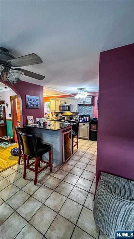 18 Trinity Pl, Kearny, NJ 07032 - bar area with a ceiling fan, stainless steel microwave, light tile patterned floors, and arched walkways