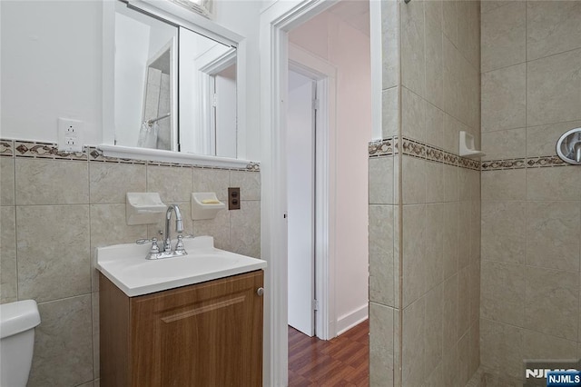548 Jefferson Ave, Elizabeth, NJ 07201 - bathroom featuring toilet, vanity, wood finished floors, a tile shower, and tile walls