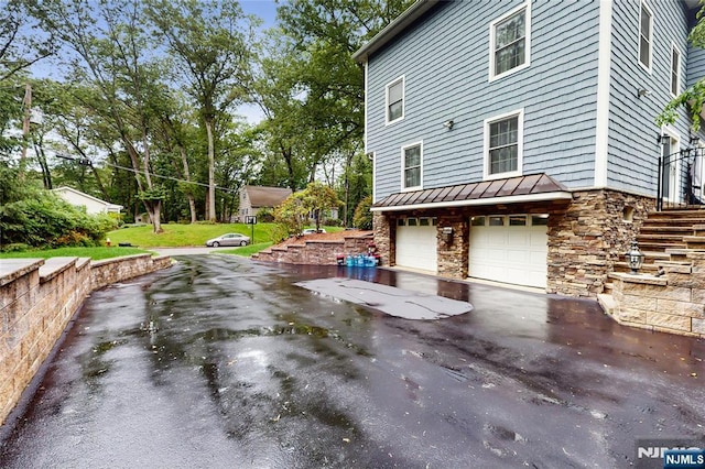 87 Skytop Dr, Mahwah, NJ 07430 - view of side of property with stone siding, a standing seam roof, an attached garage, driveway, and a metal roof