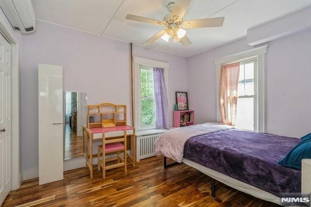129 Phelps Ave, Englewood, NJ 07631 - bedroom with radiator, an AC wall unit, wood finished floors, and ceiling fan