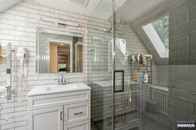 129 Phelps Ave, Englewood, NJ 07631 - full bathroom featuring vanity, a stall shower, a skylight, tile walls, and backsplash