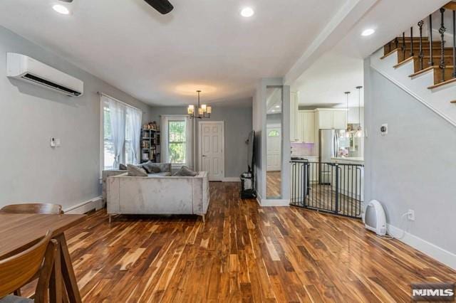 129 Phelps Ave, Englewood, NJ 07631 - living room with a wall mounted AC, wood finished floors, baseboards, a chandelier, and stairs