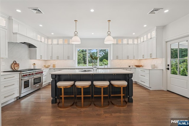 107 Rutland Rd, Glen Rock, NJ 07452 - kitchen with range with two ovens, an island with sink, a kitchen breakfast bar, light countertops, and recessed lighting