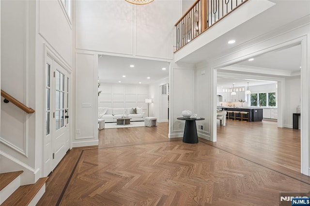 107 Rutland Rd, Glen Rock, NJ 07452 - foyer entrance with stairway, a high ceiling, a decorative wall, a chandelier, and ornamental molding