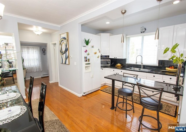 332 Summer St, Clifton, NJ 07011 - kitchen featuring white refrigerator with ice dispenser, dark countertops, stainless steel microwave, a baseboard heating unit, and light wood-style floors