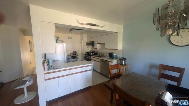 9 Meadowview Ter Unit 9, Fair Lawn, NJ 07410 - kitchen with stainless steel appliances, tasteful backsplash, a sink, white cabinetry, and light countertops