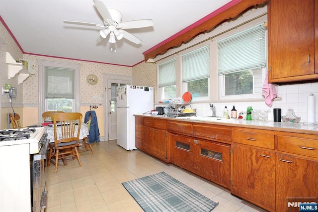 267 Hoover Ave, Bloomfield, NJ 07003 - kitchen with wallpapered walls, white appliances, a ceiling fan, a sink, and brown cabinets