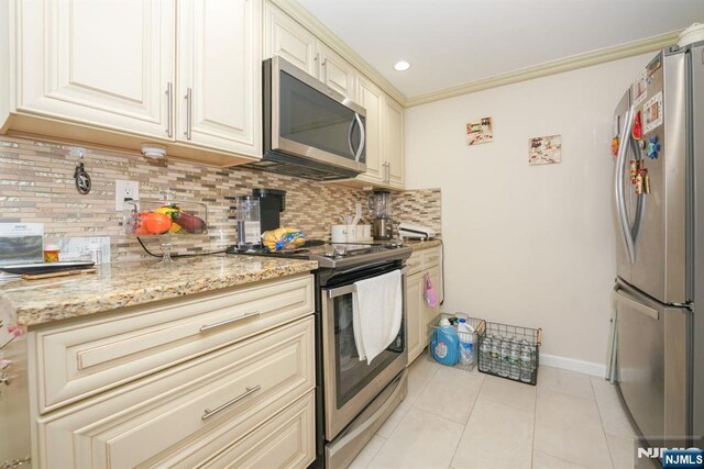 8841 Kennedy Unit 19, North Bergen, NJ 07047 - kitchen featuring appliances with stainless steel finishes, cream cabinetry, backsplash, light tile patterned flooring, and recessed lighting