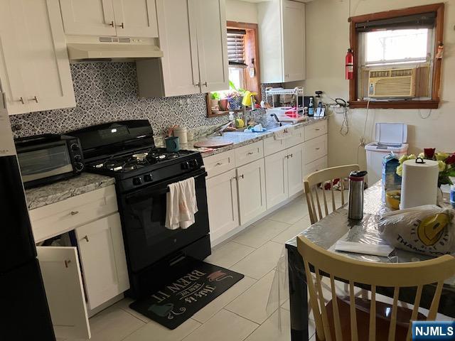 272 E Midland Ave, Garfield, NJ 07652 - kitchen with black gas range, under cabinet range hood, cooling unit, and backsplash