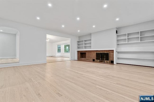 310 Spring Valley Rd, Paramus, NJ 07652 - unfurnished living room with light wood finished floors, recessed lighting, a brick fireplace, built in shelves, and baseboards