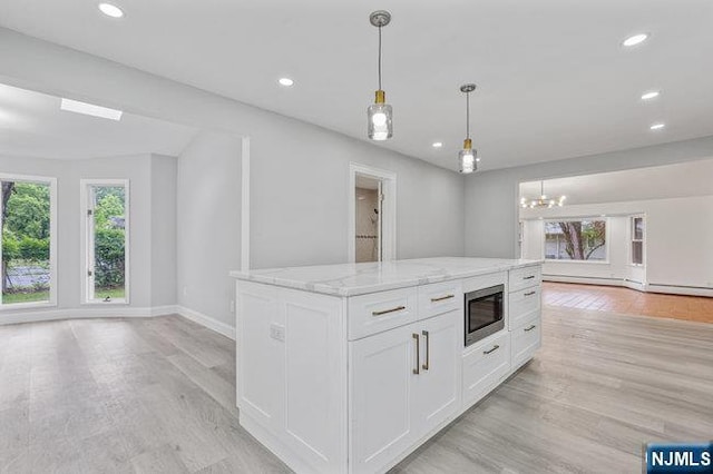 310 Spring Valley Rd, Paramus, NJ 07652 - kitchen with open floor plan, stainless steel microwave, light wood-style flooring, white cabinets, and light stone countertops