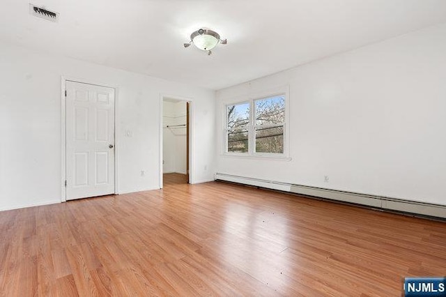 310 Spring Valley Rd, Paramus, NJ 07652 - unfurnished bedroom featuring light wood-style flooring, a baseboard heating unit, a closet, and a walk in closet