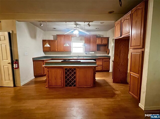 22 Clark St, Glen Ridge, NJ 07028 - kitchen featuring wood finished floors, rail lighting, brown cabinets, a center island, and baseboards
