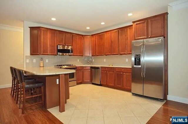 1128 43rd St Unit 1, North Bergen, NJ 07047 - kitchen with appliances with stainless steel finishes, a peninsula, baseboards, tasteful backsplash, and recessed lighting