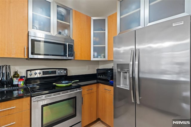 24 Ave At Port Imperial Unit 416, West New York, NJ 07093 - kitchen featuring appliances with stainless steel finishes, glass insert cabinets, and brown cabinets
