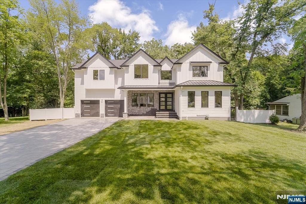 142 Ellsworth Ter, Glen Rock, NJ 07452 - view of front of house with driveway, an attached garage, a standing seam roof, a metal roof, and board and batten siding
