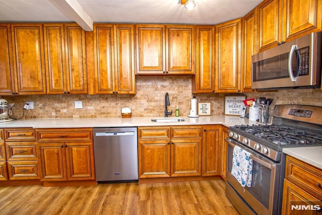 125 Virginia Ave, Dumont, NJ 07628 - kitchen featuring appliances with stainless steel finishes, a sink, brown cabinetry, wood finished floors, and beam ceiling