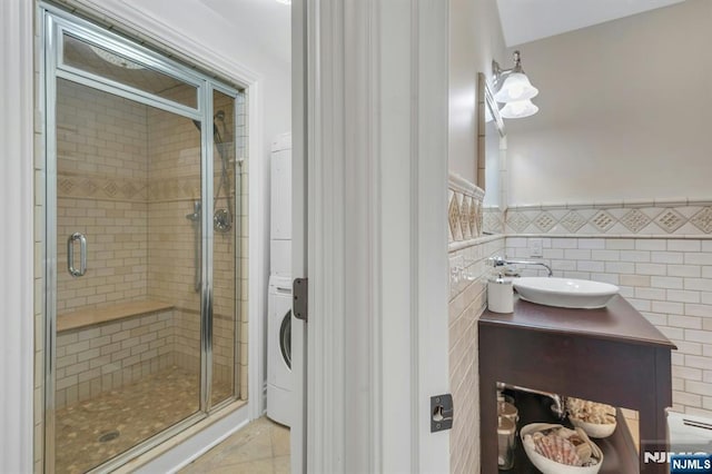 193 S Franklin Tpke, Ramsey, NJ 07446 - bathroom featuring stacked washer / drying machine, a stall shower, vanity, tile walls, and a wainscoted wall