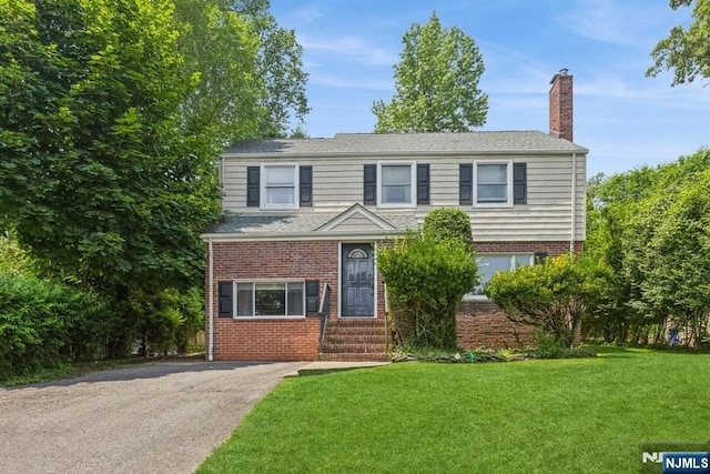 277 Jefferson Ave, Cresskill, NJ 07626 - traditional home with a chimney, a front lawn, brick siding, and asphalt driveway