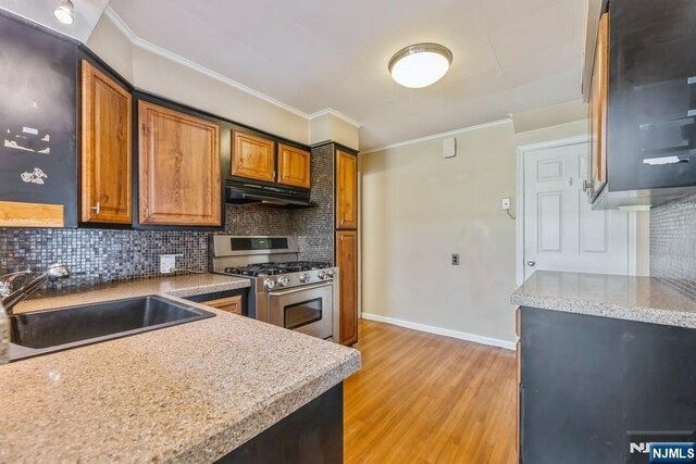 277 Jefferson Ave, Cresskill, NJ 07626 - kitchen with stainless steel gas range oven, under cabinet range hood, crown molding, a sink, and decorative backsplash