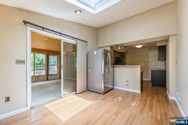 277 Jefferson Ave, Cresskill, NJ 07626 - kitchen featuring stainless steel refrigerator with ice dispenser, a skylight, light wood-style flooring, and baseboards