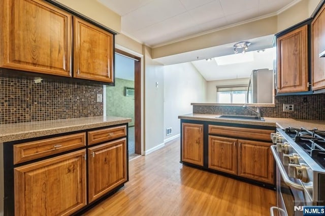 277 Jefferson Ave, Cresskill, NJ 07626 - kitchen with a sink, stainless steel gas range oven, brown cabinetry, and crown molding
